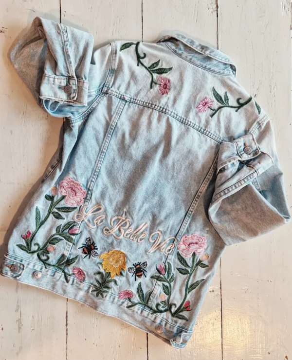 Veste en denim brodée de fleurs avec inscription sur le bas du dos « la belle vie»