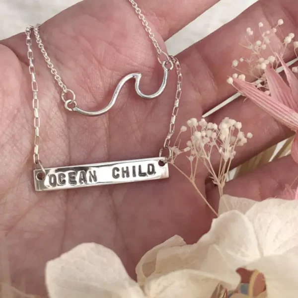 Collier gravé à la main avec l'inscription « Ocean Child », en français « Enfant de l'océan ».