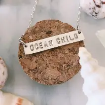 Collier gravé à la main avec l'inscription « Ocean Child », en français « Enfant de l'océan ».