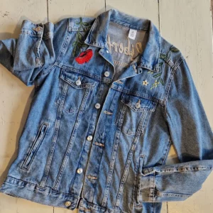 Veste en denim brodée de fleurs et de papillons avec inscription sur le haut du dos « liberté »