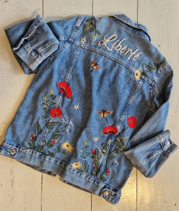 Veste en denim brodée de fleurs et de papillons avec inscription sur le haut du dos « liberté »